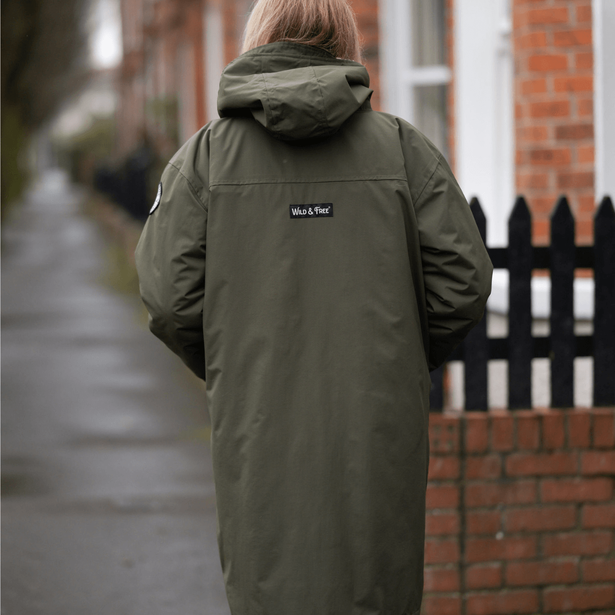 Raincoat & Changing Robe in One - The Classic Cobe Olive Green worn in a rain-soaked urban setting.