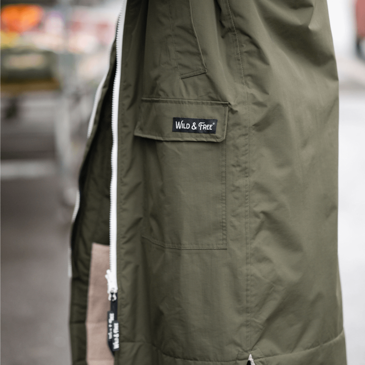 Raincoat & Changing Robe in One - The Classic Cobe Olive Green close-up of pocket with Wild & Free logo