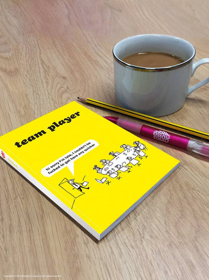 Yellow Modern Toss Team Player A6 notebook on a wooden desk beside a mug and pencils