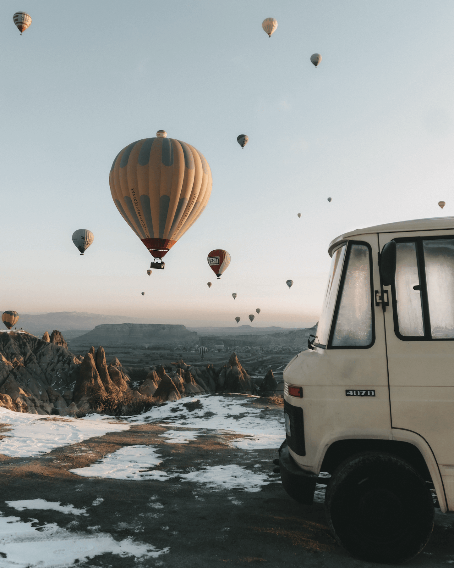 Van parked on a scenic landscape with hot air balloons in the sky