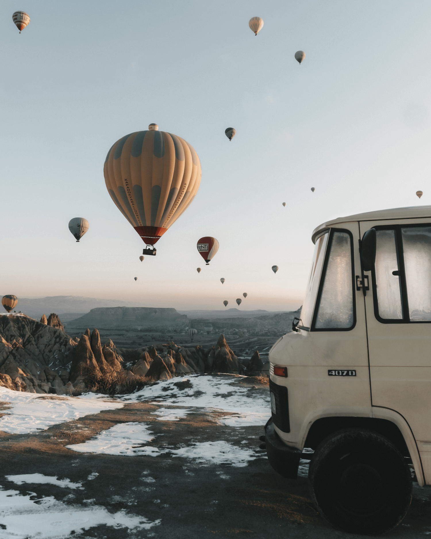 Van parked on a scenic landscape with hot air balloons in the sky