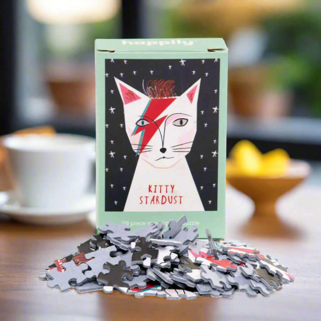 Happily Kitty Stardust puzzle box with scattered puzzle pieces on a table.