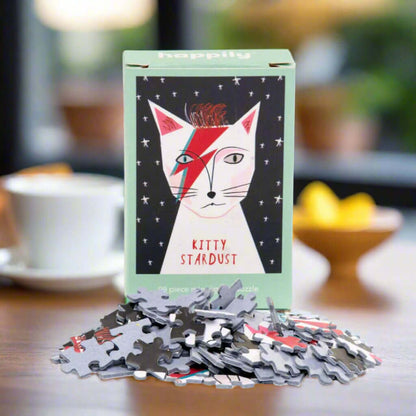 Happily Kitty Stardust puzzle box with scattered puzzle pieces on a table.