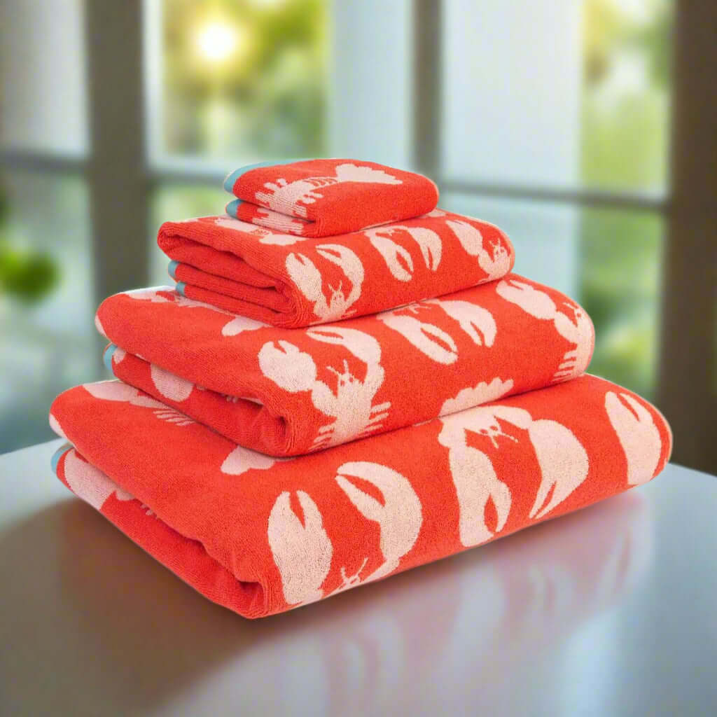 Stack of red towels with white lobster patterns on a white background