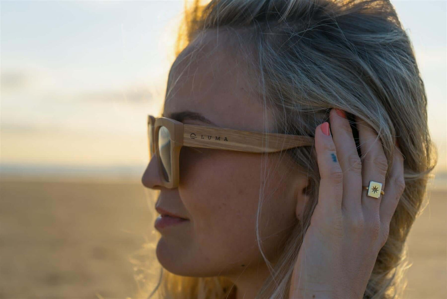 Luma Sunglasses - Polzeath - Brown worn by a woman on the beach, showcasing eco-friendly fashion in the UK.