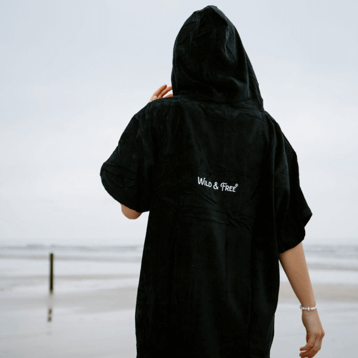 A person wearing The Luxury Towel Robe by Wild & Free®, enjoying a beach day.
