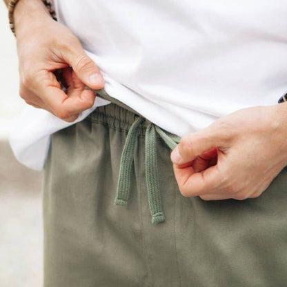 Close-up of hands adjusting the drawstring on Men's Sandbar Organic Cotton Shorts for a perfect fit.
