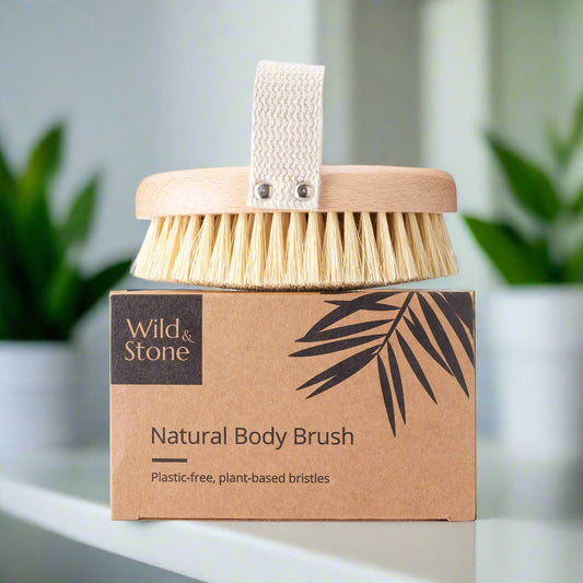 Natural body brush with wooden handle and plant-based bristles on a cardboard packaging labeled 'Wild & Stone'.