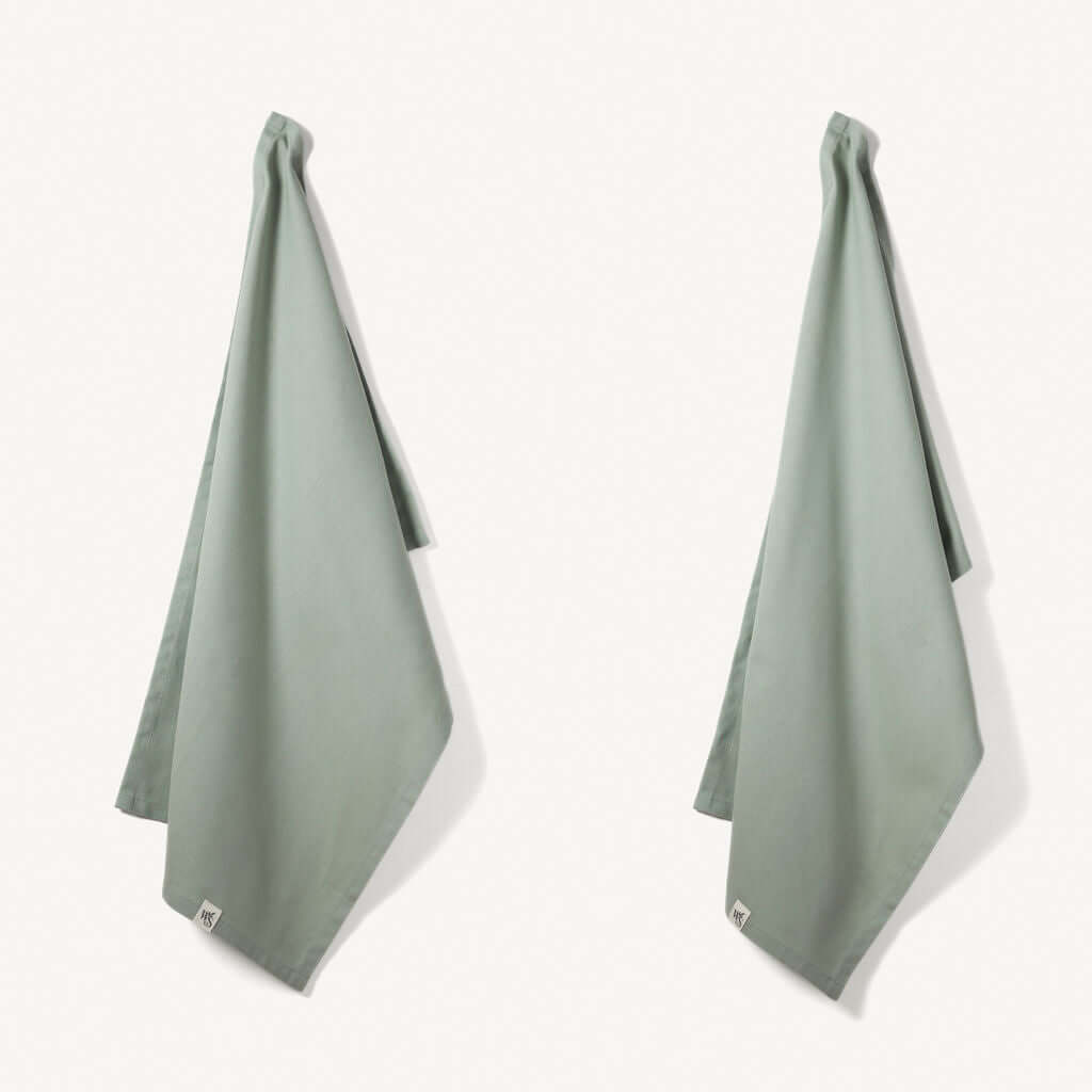 Organic Cotton Tea Towels - Herringbone Weave - Set of 2 hanging in a kitchen, showcasing their absorbent and stylish design.