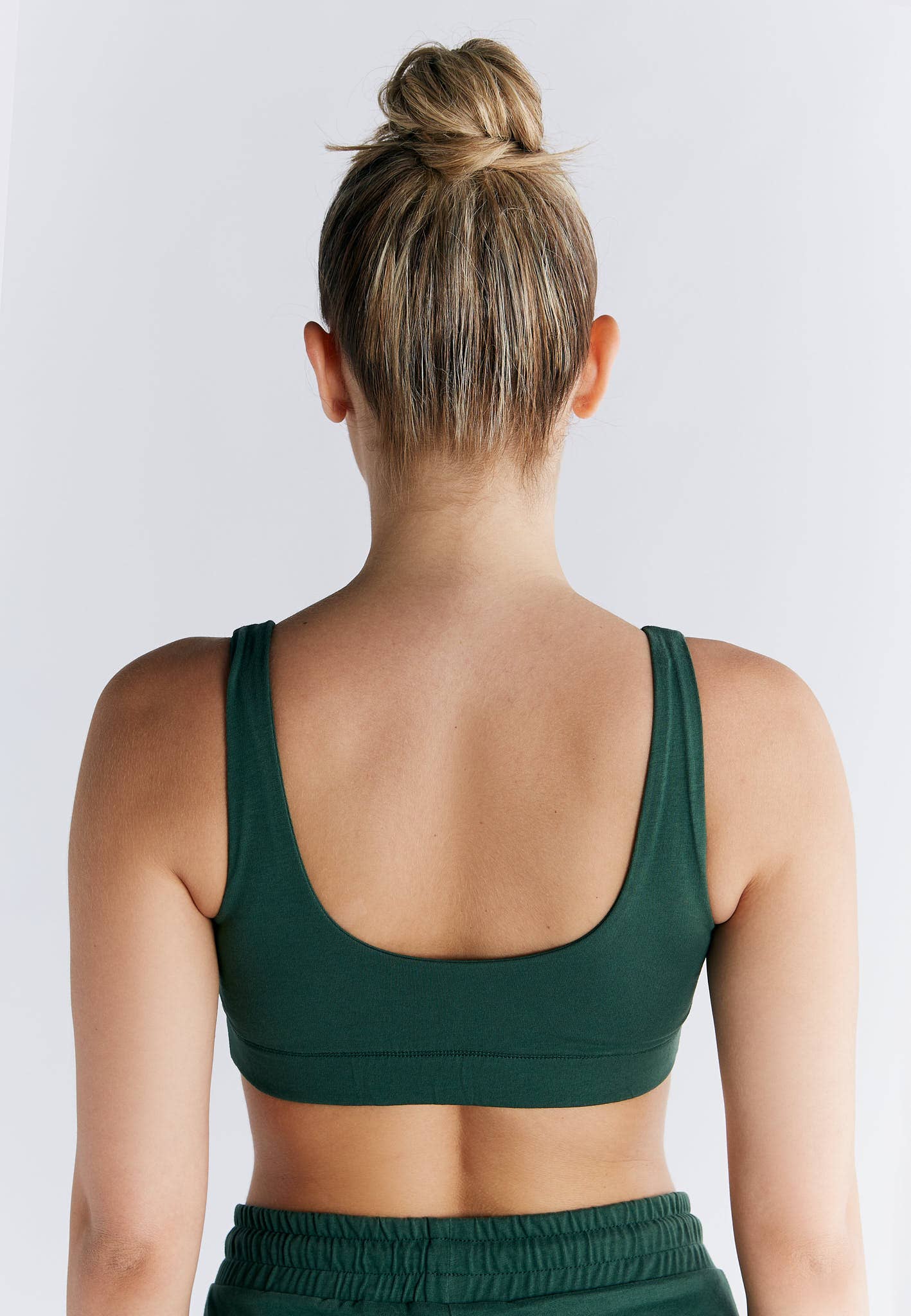 Back view of a woman wearing an Organic Cotton Padded Bralette in green, showcasing the supportive design and broad straps.