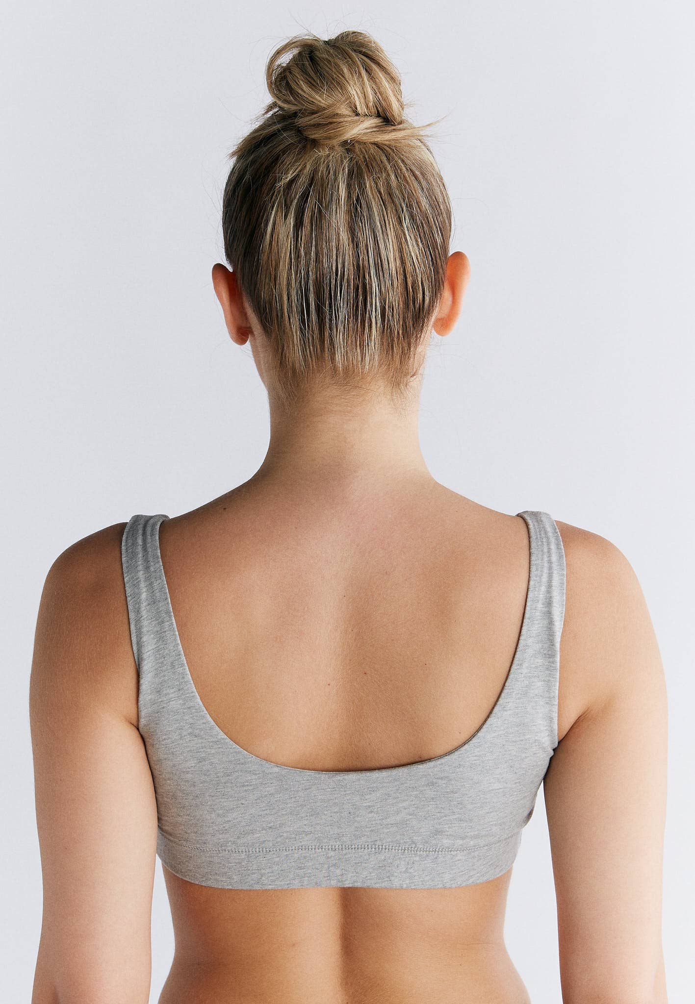 Back view of a model wearing an Organic Cotton Padded Bralette in grey, showcasing its supportive design and comfort.