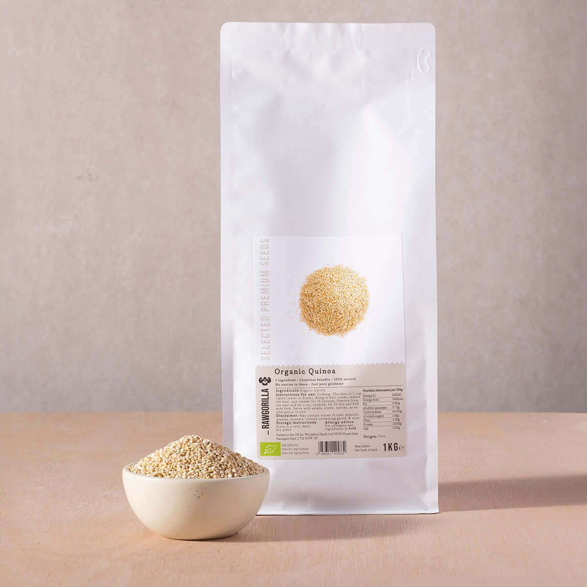 White bag of organic quinoa with a bowl of quinoa on a beige background