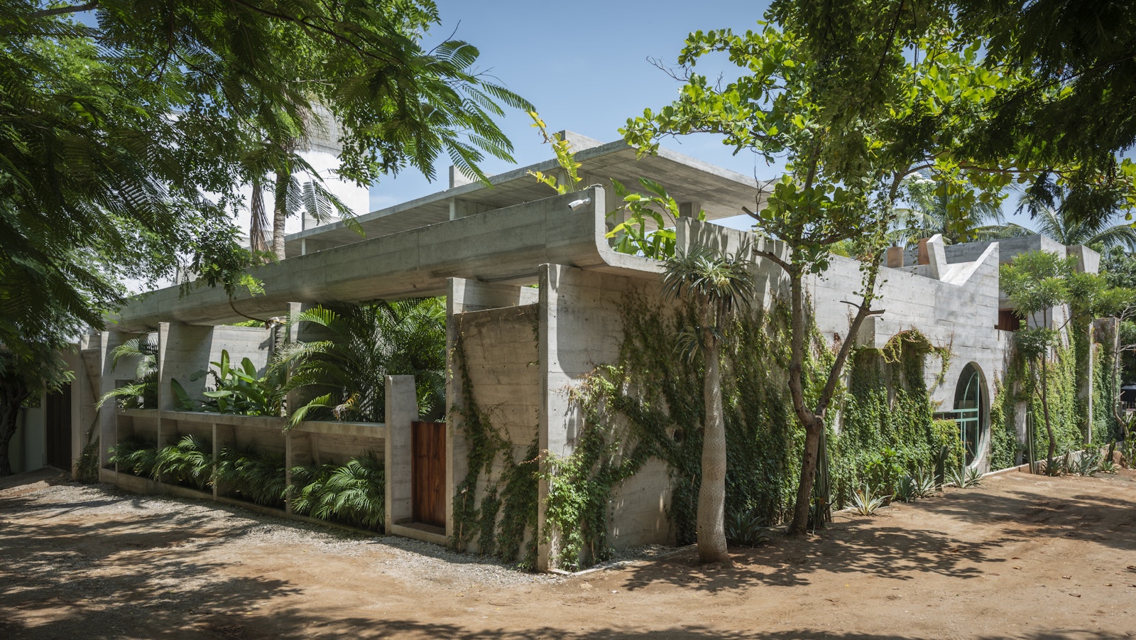 Modern building with greenery integrated into its design, surrounded by trees.
