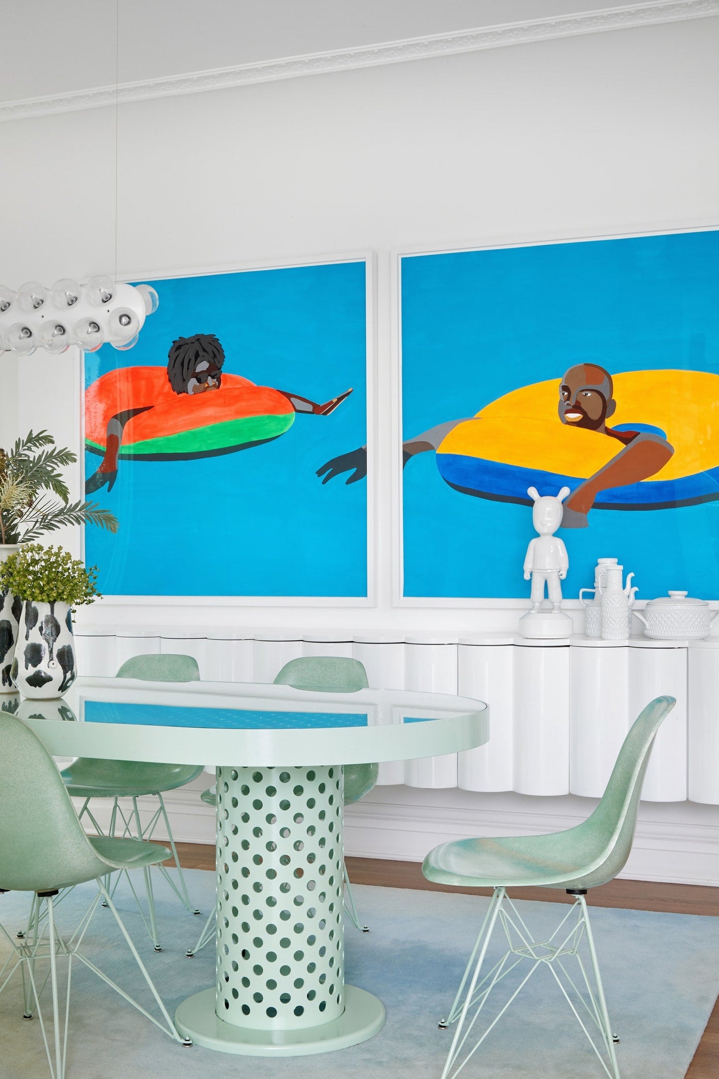 Dining room with a modern table and chairs, featuring two large abstract paintings on the wall.