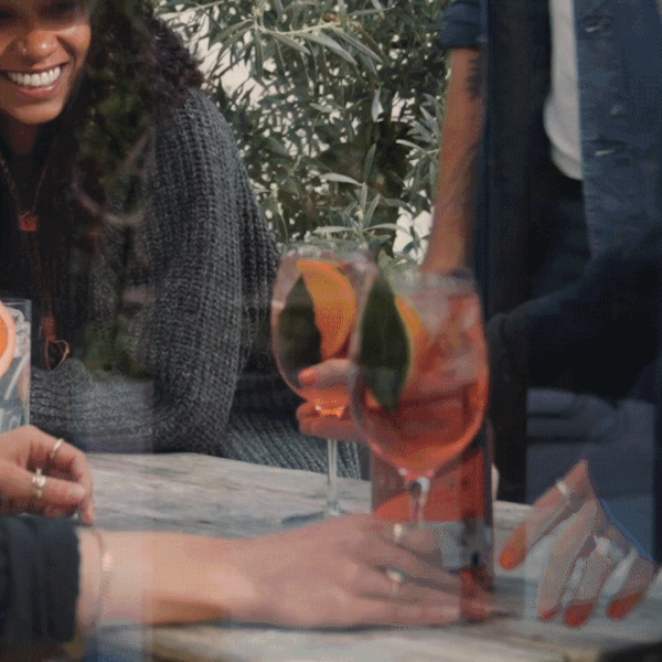 Friends enjoying Pentire Coastal Spritz cocktails outdoors, featuring vibrant garnishes and refreshing colors.