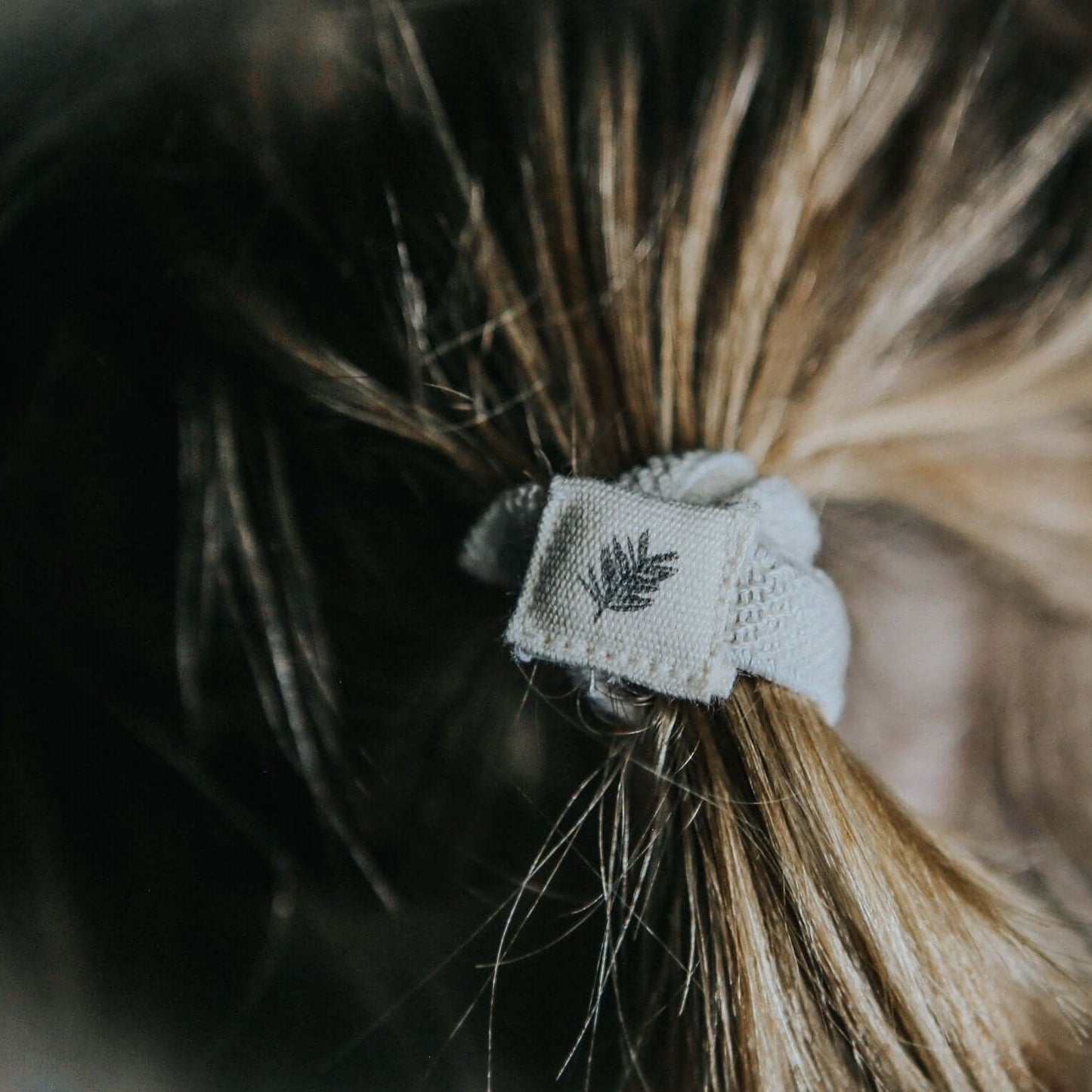 Close-up of a hair tie with a leaf design in a person's hair
