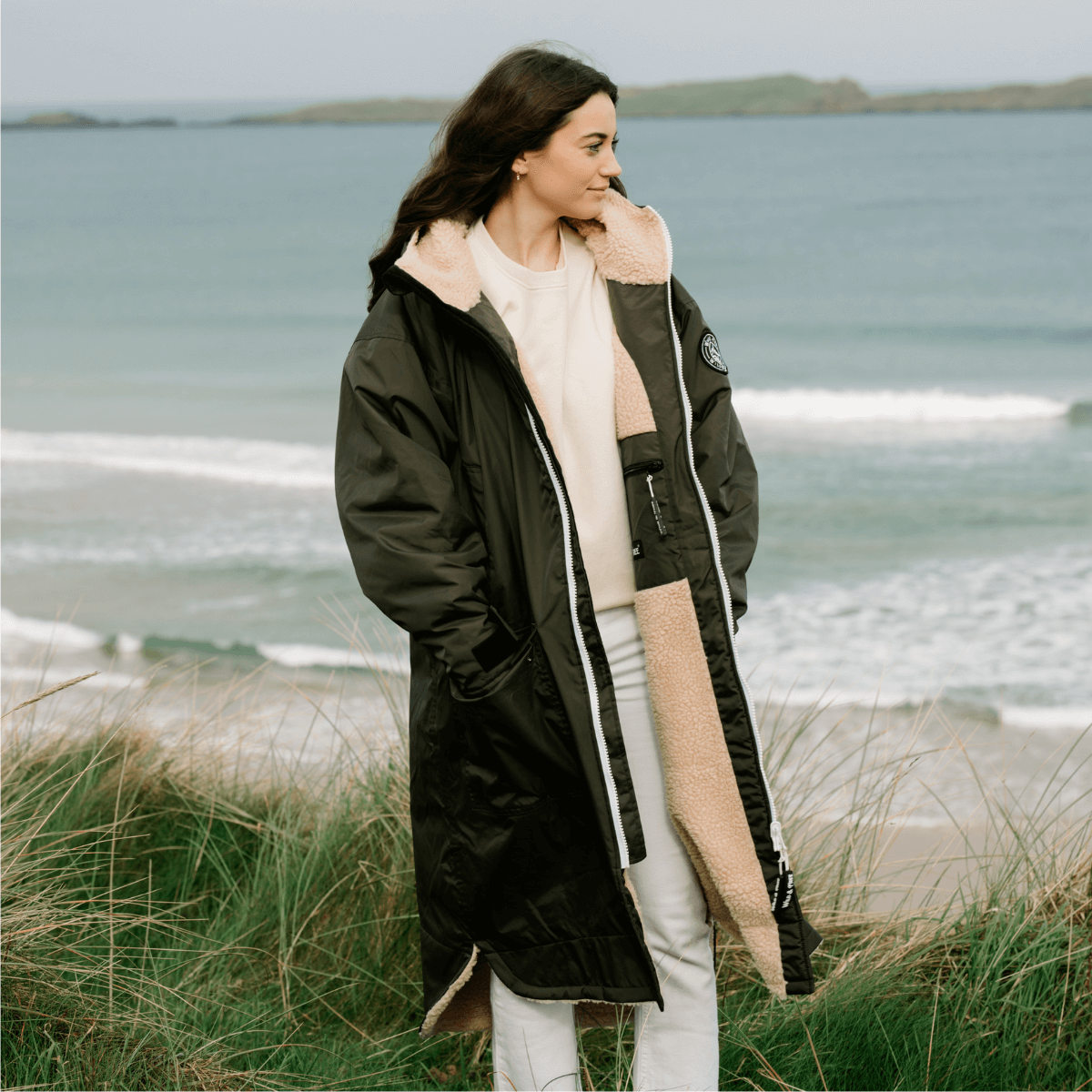 Raincoat & Changing Robe in One - The Classic Cobe Olive Green worn by a woman on a beach.