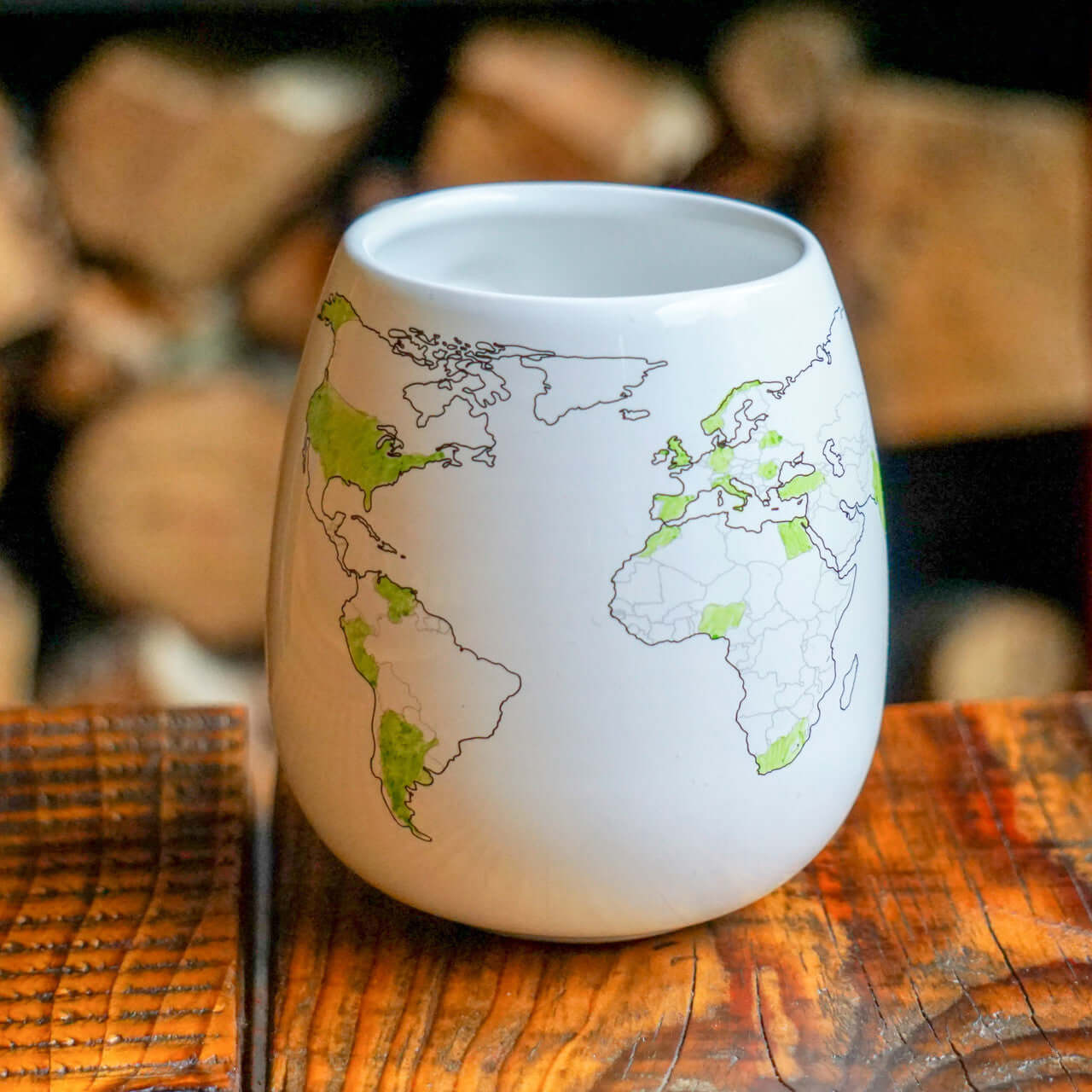 White ceramic cup with world map design on a wooden surface