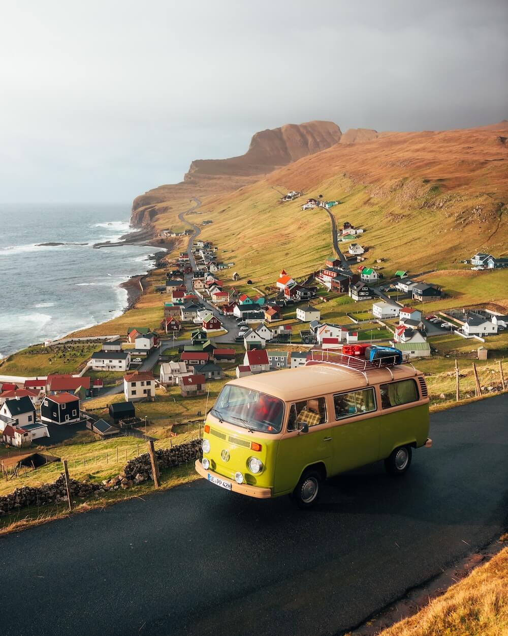 Vintage van on a coastal road with a scenic village and ocean view