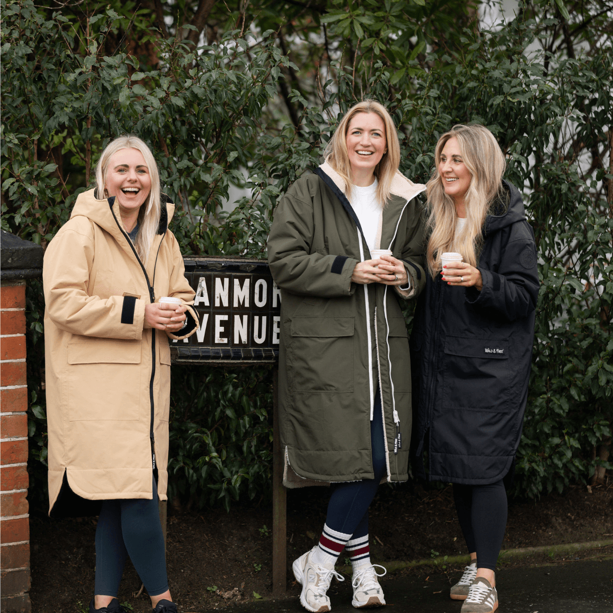 Raincoat & Changing Robe in One - The Classic Cobe Olive Green worn by three women, laughing outdoors.