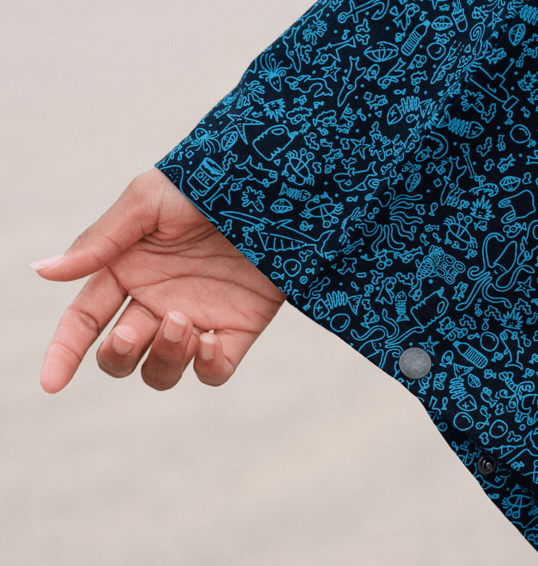 Close-up of a hand reaching out, showcasing the fun marine-inspired print of a water-repellent rain poncho.