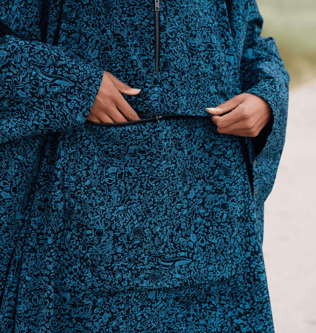 Model wearing a water-repellent rain poncho with a marine-inspired print and a front pocket.