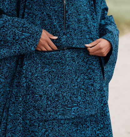 Model wearing a water-repellent rain poncho with a marine-inspired print and a front pocket.
