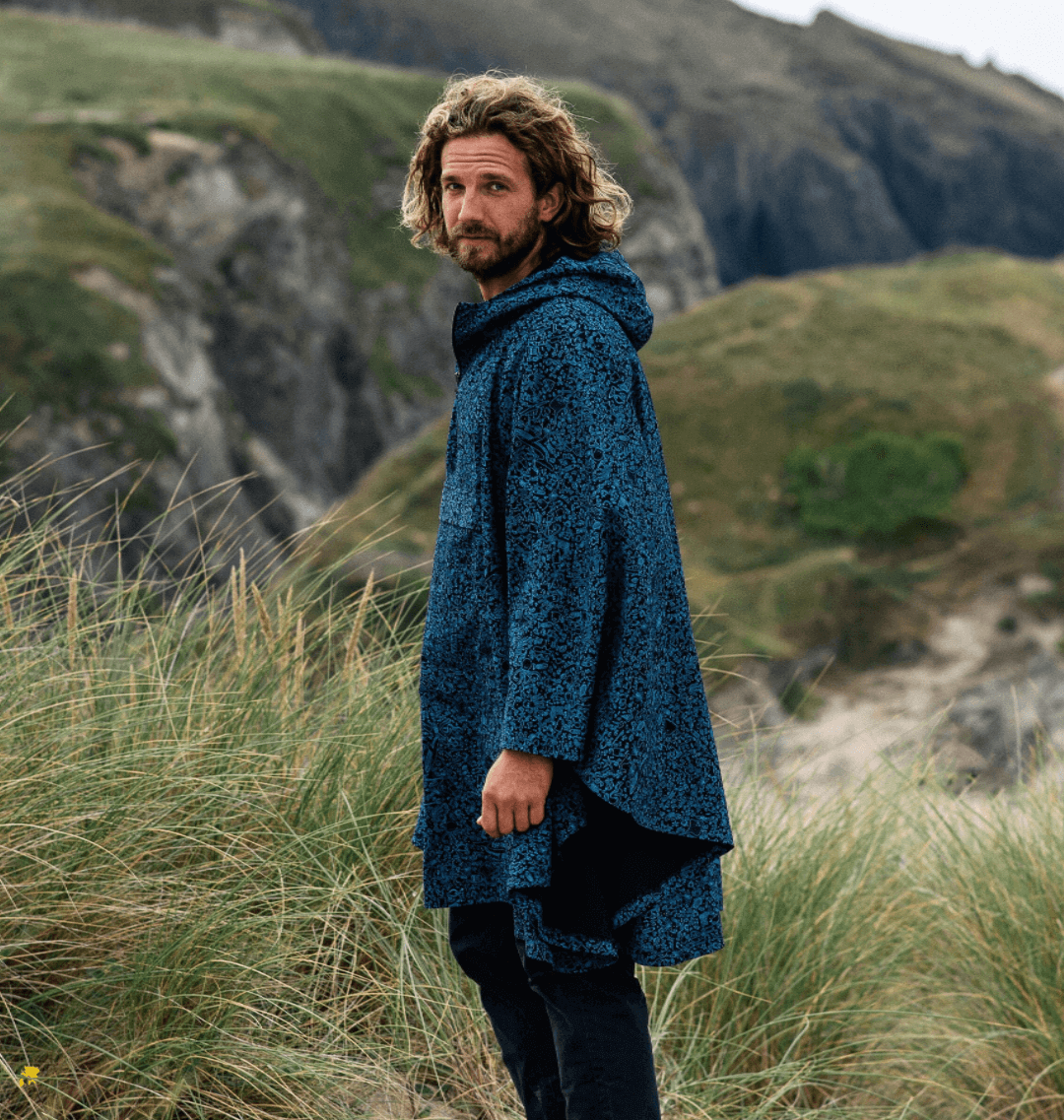 Man wearing a stylish Water-Repellent Rain Poncho against a coastal backdrop, showcasing eco-friendly fashion.