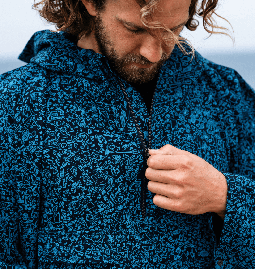 Man zipping up a Water-Repellent Rain Poncho with a marine-inspired print, perfect for eco-conscious fashion.