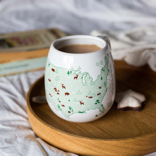 White mug with nature-themed design on a wooden tray