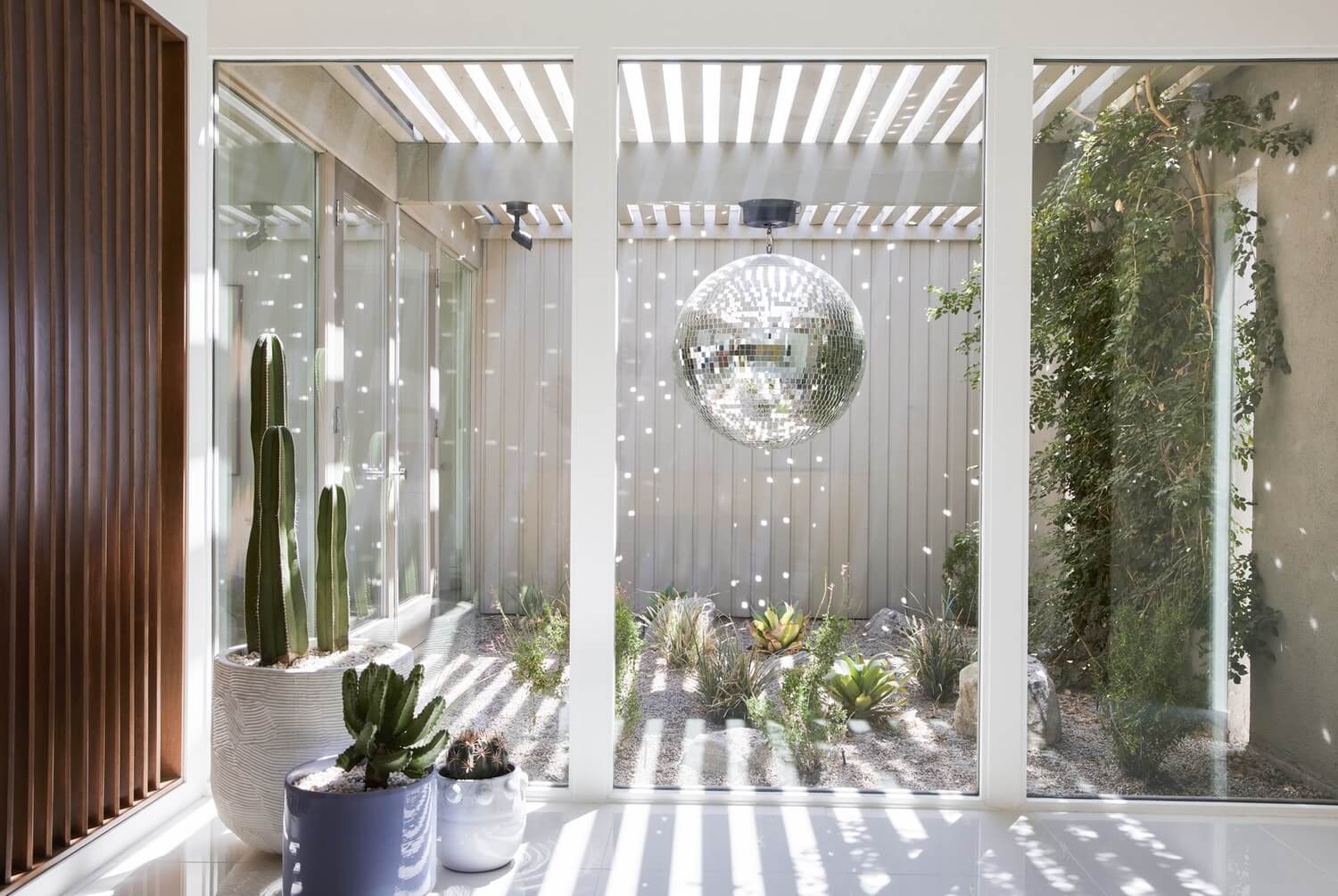Modern interior with large glass doors, plants, and a decorative mirror.