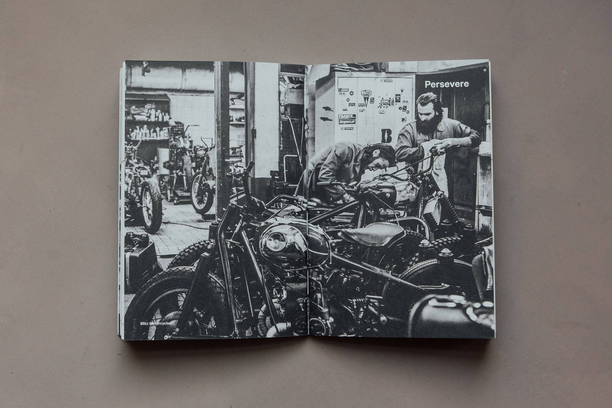 Black and white image of a motorcycle workshop with men working on bikes, titled 'Persevere'.