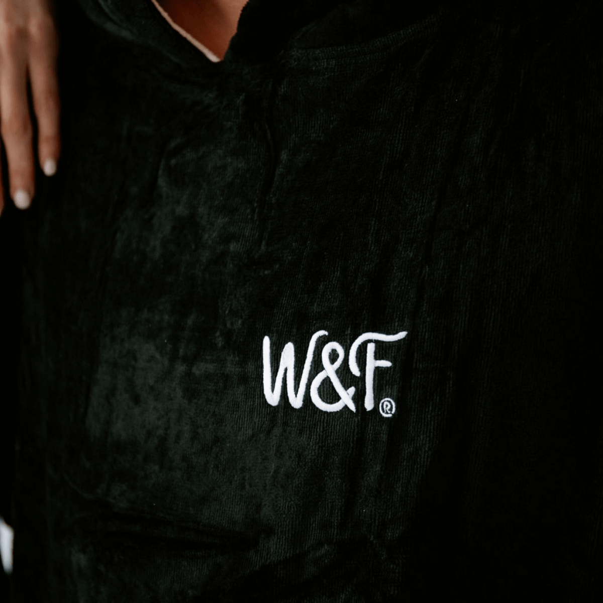 The Luxury Towel Robe featuring W&F® logo on a soft black velour fabric for stylish comfort.