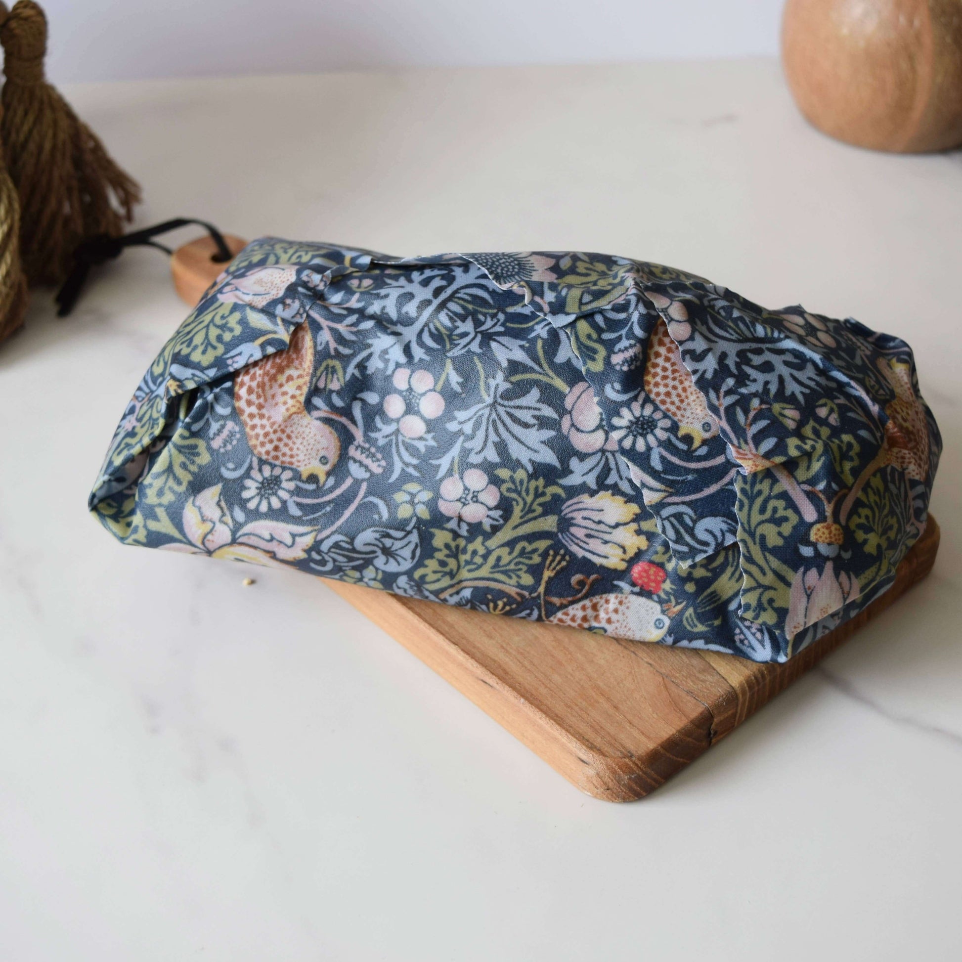 Floral-patterned fabric roll on a wooden board with a white background