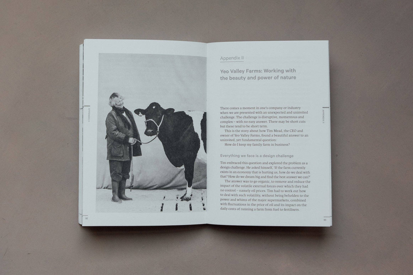 Open book showing a black and white photograph of a person with a cow and text on a brown background